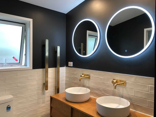 Bathroom with backlit circular mirrors.