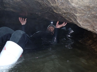 Leading Edge team member swimming in dark cave